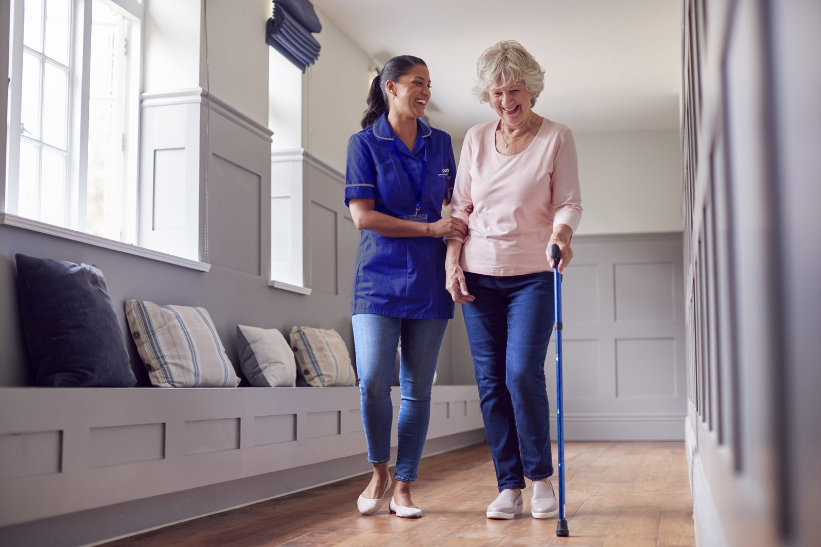 A caregiver helping a resident walk with a cane