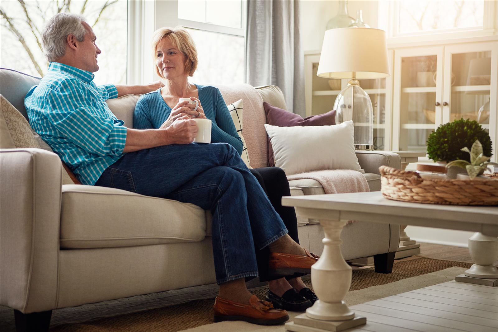 A senior couple chatting over coffee on their sofa at home